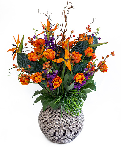 Striking orange and purple artificial flower arrangement in round vase