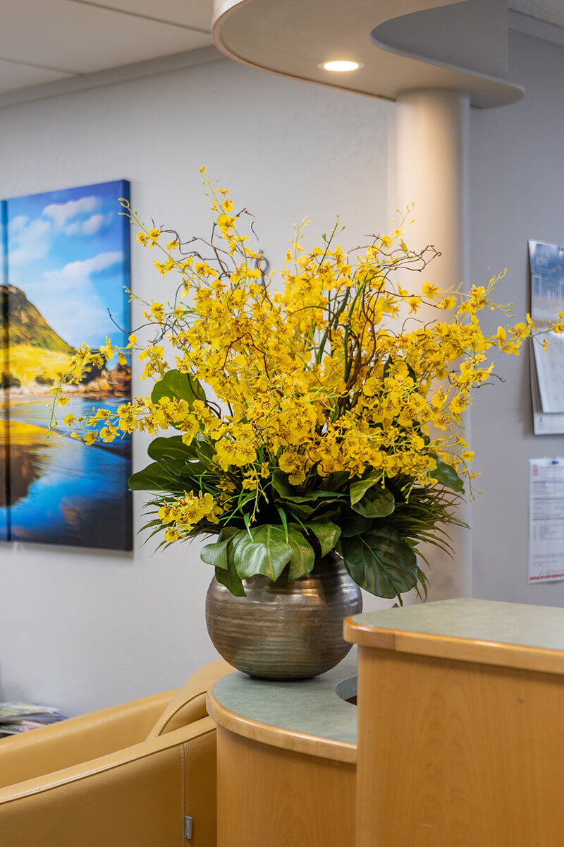 Yellow artificial flower arrangement on reception desk in office
